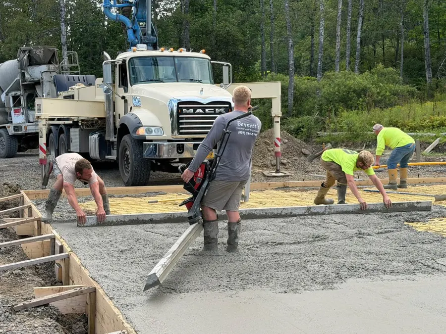 Bennett's crew screeding a slab pour with a concrete pump truck and mixer behind them