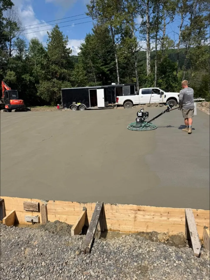 Power troweling a fresh slab, with the Bennett's trailer, pickup and mini excavator behind